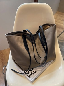 Grand sac fourre-tout en nylon olive avec bandoulières en cuir noir sur chaise blanche