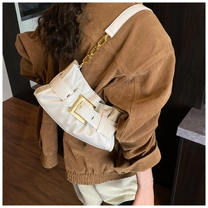 Detail of white ruched underarm bag with large gold square buckle and chain strap