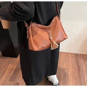 Detail der karamellbraunen Schultertasche aus Cord mit elegantem Quastenanhänger
