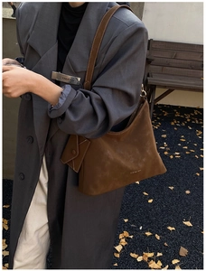 Outdoor street shot of a deep brown suede hobo bag with a matching mini pouch