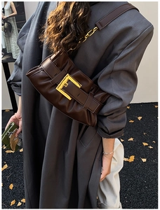 Detail of dark brown pleated handbag with oversized gold buckle and chain strap