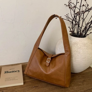 Detail der karamellbraunen New Moon Tasche mit Retro-Schnalle auf Holzoberfläche