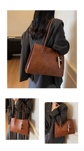 Detail of brown tote bag with beaded tassel charm and vintage wax leather texture