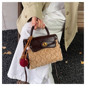 Detail of heart textured plush handbag with brown leather flap and red tassel charm