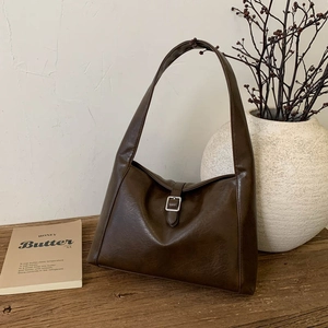 Vintage dunkelbraune Hobo-Tasche mit Silberschnalle auf einem rustikalen Holztisch