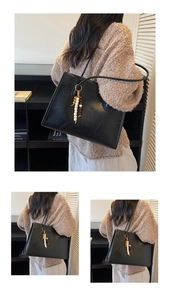 Detail showing high-capacity black PU leather tote bag with a decorative beaded pendant charm