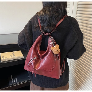 Detail of burgundy large capacity tote backpack with silver zipper and bear charm