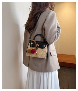 Detail of heart-quilted plush handbag with leather lid and decorative pom-poms on model
