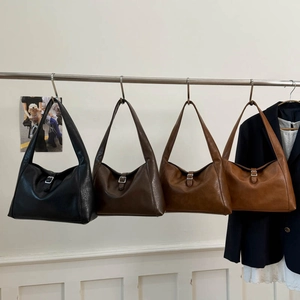 Vintage-Halbmondtaschen in Schwarz, Dunkelbraun und Hellbraun an einem Metallständer