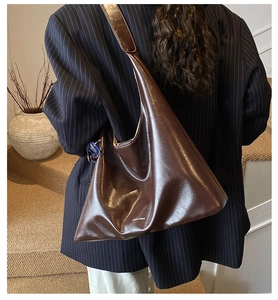 Brown slouchy leather shoulder bag worn by model with minimalist interior background