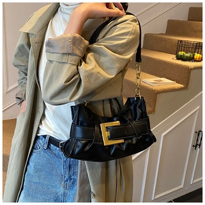 Detail of black leather underarm bag featuring a gold buckle and metal chain strap