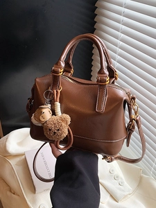 Bolso retro marrón con patrón de lichi y colgante de oso sobre blazer blanco