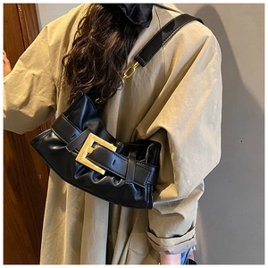 Detail of black pleated cloud bag with chunky gold buckle and chain shoulder strap