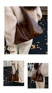 Detail view of brown vintage leather tote bag with wide strap and white logo text