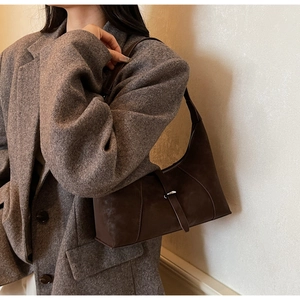 Close-up of a retro dark brown hobo bag with a silver buckle on a tweed blazer