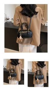 Détail du sac boston en cuir noir avec texte embossé et un pendentif en peluche marron