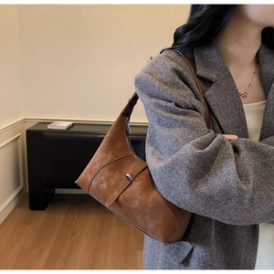 Detail of dark brown leather shoulder bag with vintage oil-wax texture and silver buckle