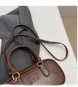 Vue détaillée du cuir marron foncé grainé et des ferrures métalliques dorées du sac