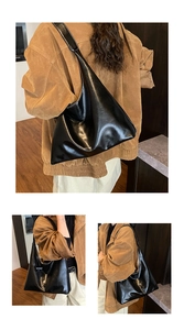 Detail view of large glossy black tote bag with wide strap paired with a brown suede jacket