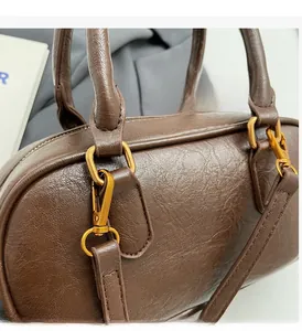 Détail du sac à main en cuir marron foncé ciré avec ferrures dorées vintage et bandoulière