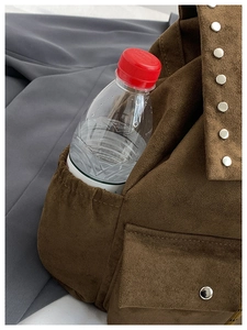 Détail macro du sac à dos en daim marron montrant une poche latérale pratique pour bouteille