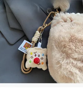 Détail du sac en peluche beige avec chaîne de perles, poignée tissée et breloque brodée