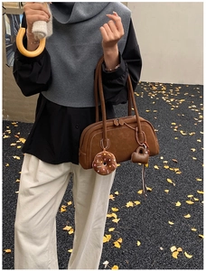 Close-up of brown suede Boston bag featuring decorative heart and donut charms