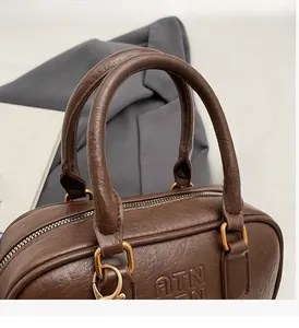 Détail de la poignée en cuir marron avec boucle dorée et logo ATN embossé sur le sac