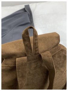 Détail d'un sac à dos en suède marron montrant la poignée et les coutures de qualité