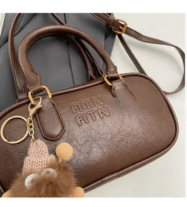 Détail d'un sac Boston rétro en cuir PU marron avec logo ATN gaufré et boucles dorées