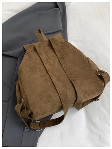 Vue détaillée d'un sac à dos en daim marron avec boucles métalliques et poche latérale