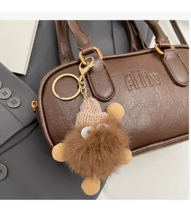 Porte-clés monstre en peluche marron avec bonnet suspendu à un sac à main en cuir