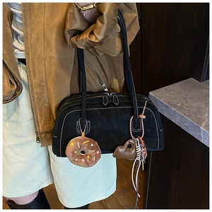 Detail of black suede bowling bag with white stitching and plush donut bag charm