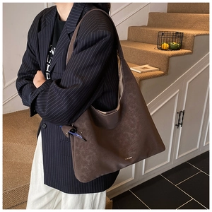 Close-up of large tote bag in coffee suede with gold stamped logo and wide strap detail