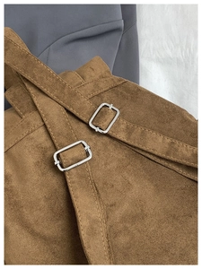 Détail des bretelles de sac à dos en daim marron avec boucles en métal et surpiqûres