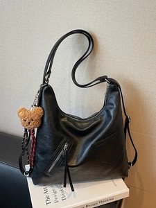 Large black textured tote bag for women with cute bear pendant on a white design book