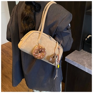 Detail of beige faux leather tote bag featuring cute plush doughnut and heart charms