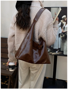 Detail of brown soft leather tote bag showing glossy texture and spacious slouchy design