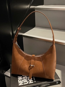 Retro caramel suede hobo bag with silver buckle on urban book setting