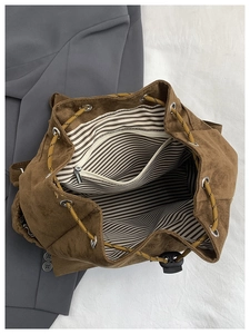 Détail d'un sac à dos en daim marron avec doublure rayée et fermeture à cordon coulissant