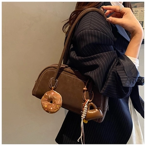 Detail of brown vintage frosted shoulder bag with white contrast stitching and cute charms