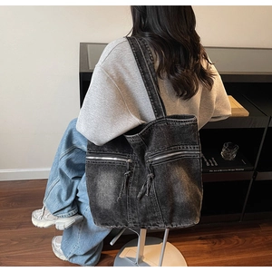 Gros plan sur un cabas en denim gris vintage avec deux poches zippées et tissu texturé