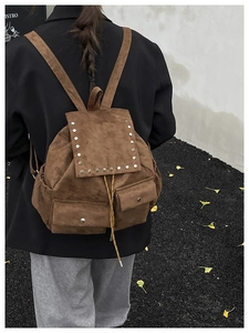 Détail du sac à dos vintage en daim marron avec rivets et deux poches frontales