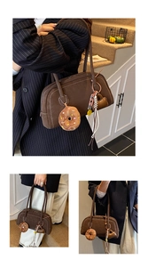 Detail view of brown faux suede baguette bag with contrast stitching and plush charms
