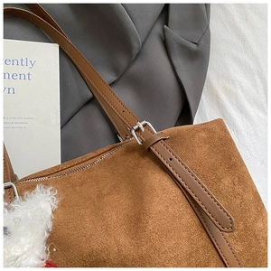 Detailed macro view of brown suede tote bag with zip closure and adjustable leather strap