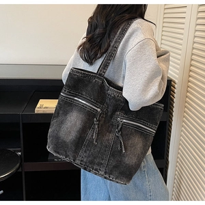 Détail du sac cabas en denim noir vintage avec poches à zip métallique porté à l'épaule