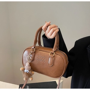 Détail du sac à main marron en cuir grainé avec logo et breloque en peluche douce