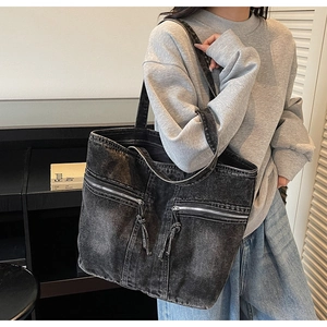 Detail view of washed denim tote bag with dual front zippers and vintage gray finish