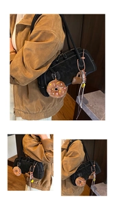 Detail of black matte suede Boston bag with plush donuts and beaded tassel charms