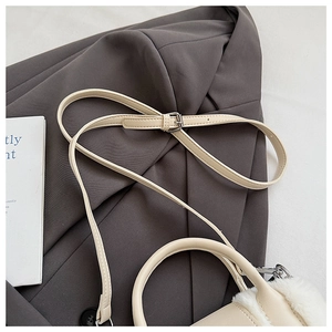 Detail of beige faux leather bag with white plush trim and adjustable silver buckle strap
